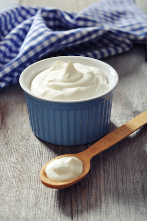 A bowl of plain yogurt and a spoon.