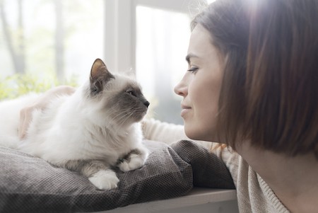 A woman and her cat look lovingly at each other.