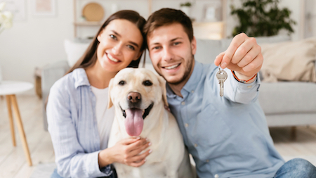 A couple and their retriever pose with their new house key.